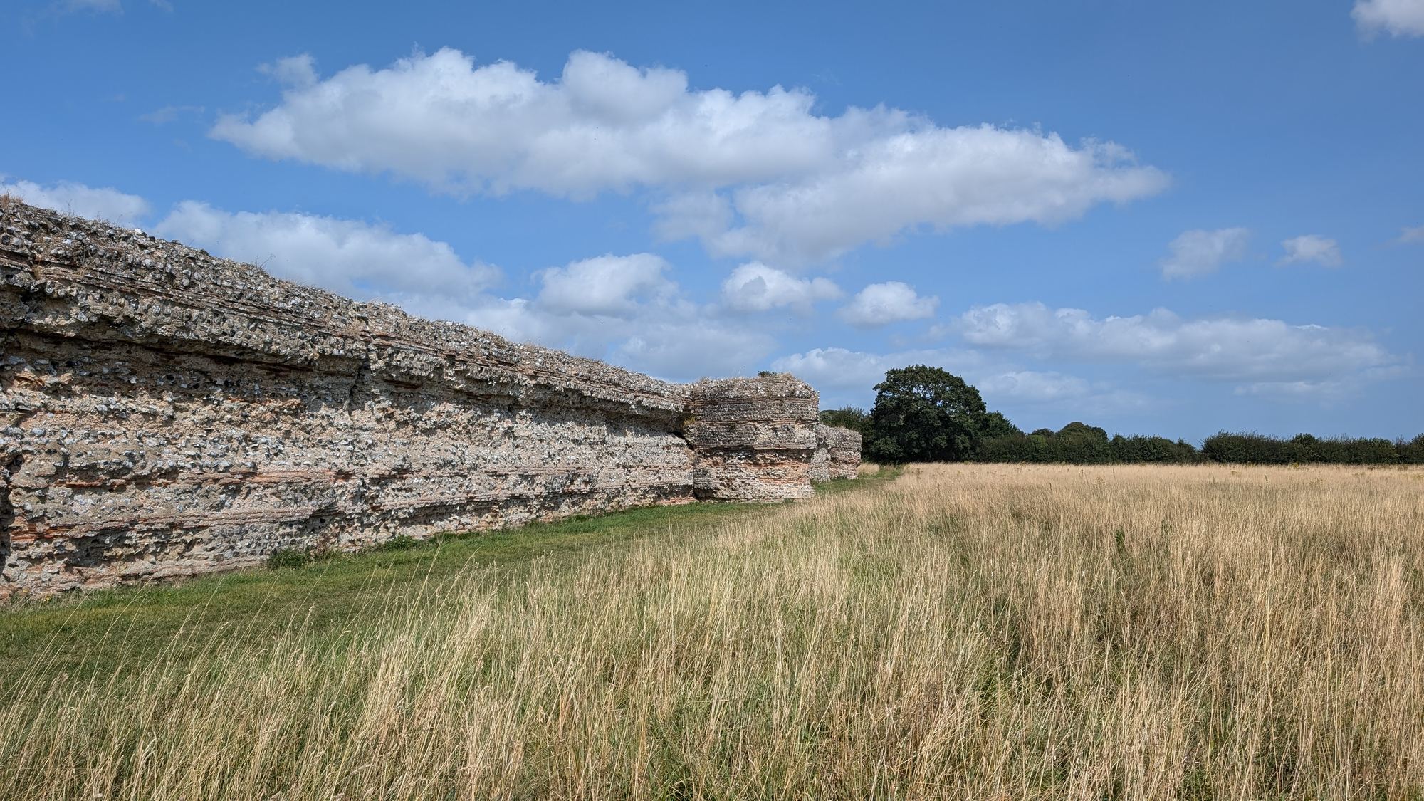 The Roman fort walls at Burgh Castle, Norfolk, with long grass in the foreground